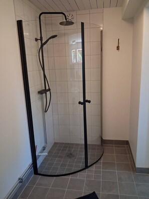 A glass-enclosed shower with a curved design, tiled walls, and a tiled floor. - Cozy place near nature and bath (Bullaren)