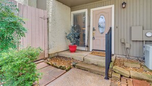 Une entrée de maison avec une porte, des marches, un plant en pot rouge et une boîte aux lettres.