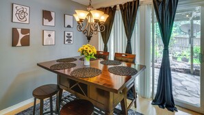 Un coin repas avec une table en bois, des chaises, un lustre et des œuvres d’art accrochées au mur.