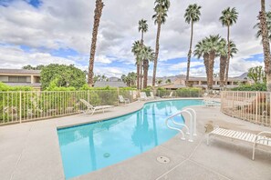 A swimming pool with lounge chairs and palm trees. - Private Hot Tub + Rooftop Patio: Palm Desert Oasis (Palm Desert)