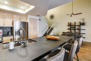 A modern kitchen with a central island, stainless steel appliances, and a dining area with chairs and a table. - Private Hot Tub + Rooftop Patio: Palm Desert Oasis (Palm Desert)