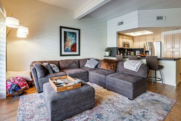 A living room with a sectional sofa, a coffee table, and a rug. - Private Hot Tub + Rooftop Patio: Palm Desert Oasis (Palm Desert)