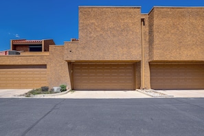 A building with two garage doors, a textured facade, and a clear blue sky. - Private Hot Tub + Rooftop Patio: Palm Desert Oasis (Palm Desert)