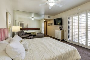 A hotel room with a bed, a desk, a chair, a TV, and a large window with blinds. - Private Hot Tub + Rooftop Patio: Palm Desert Oasis (Palm Desert)