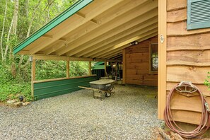 A wooden cabin with a gravel floor, a wheelbarrow, and a hose. - Cozy Little Cabin to Make Lasting Memories (Franklin)