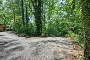 A gravel parking area with a wooden cabin and a flagpole. - Cozy Little Cabin to Make Lasting Memories (Franklin)