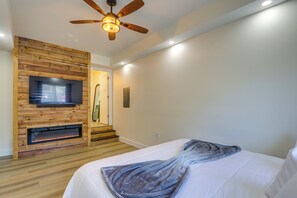 Ein Schlafzimmer mit Holzwand, Deckenventilator, Fernseher, Kamin und einem Bett mit Decke.