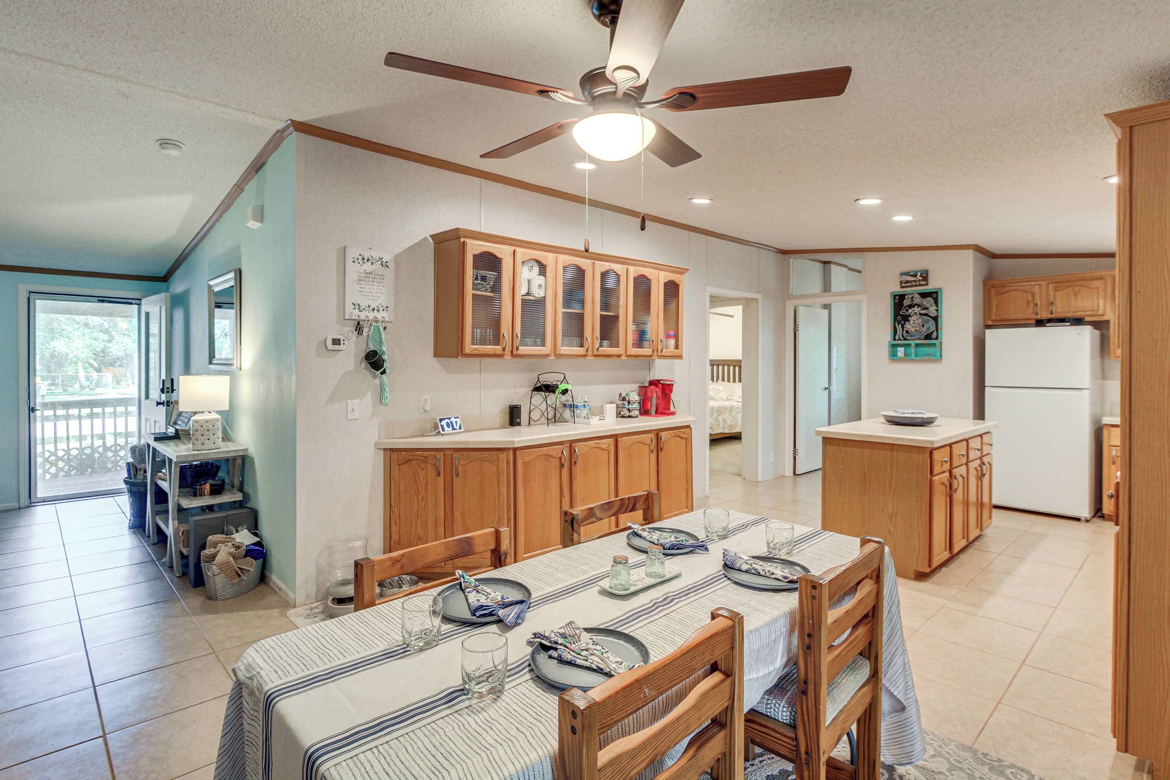 A spacious kitchen with wooden cabinets, a dining table set for four, and a ceiling fan.