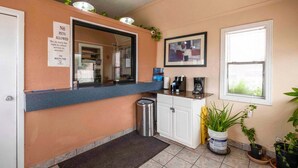 Zona de recepción con mostrador, un bote de basura, espacio para café y un cuadro en la pared.