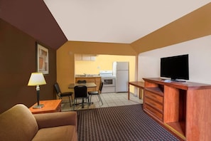 Habitació d'hotel compacta amb zona cuina, televisió, sofà i menjador.