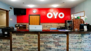 A reception desk with a red wall, a clock, and a wooden door. - 2 Full Beds | Non-Smoking (Redwood Falls)