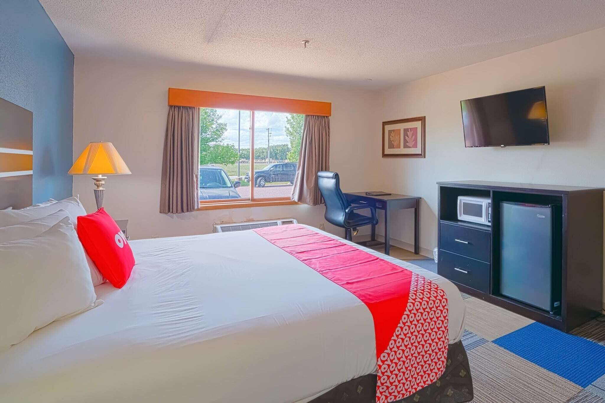Una habitación de hotel con cama, escritorio, televisión y microondas.
