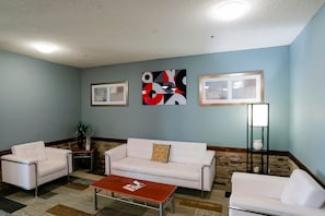 A room with a white sofa, a coffee table, and a framed picture on the wall.