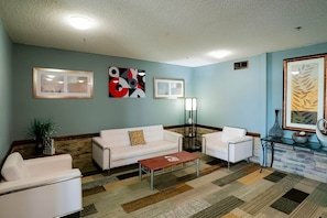 A living room with a sofa, armchairs, a coffee table, and artwork on the walls. - Studio | Non-Smoking |Redwood Falls (Redwood Falls)
