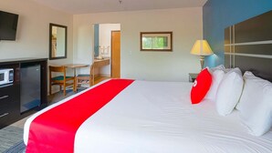 Une chambre d’hôtel équipée d’un lit, d’un bureau, d’un four à micro-ondes, d’une télévision et d’une salle de bain visible à travers une porte ouverte.