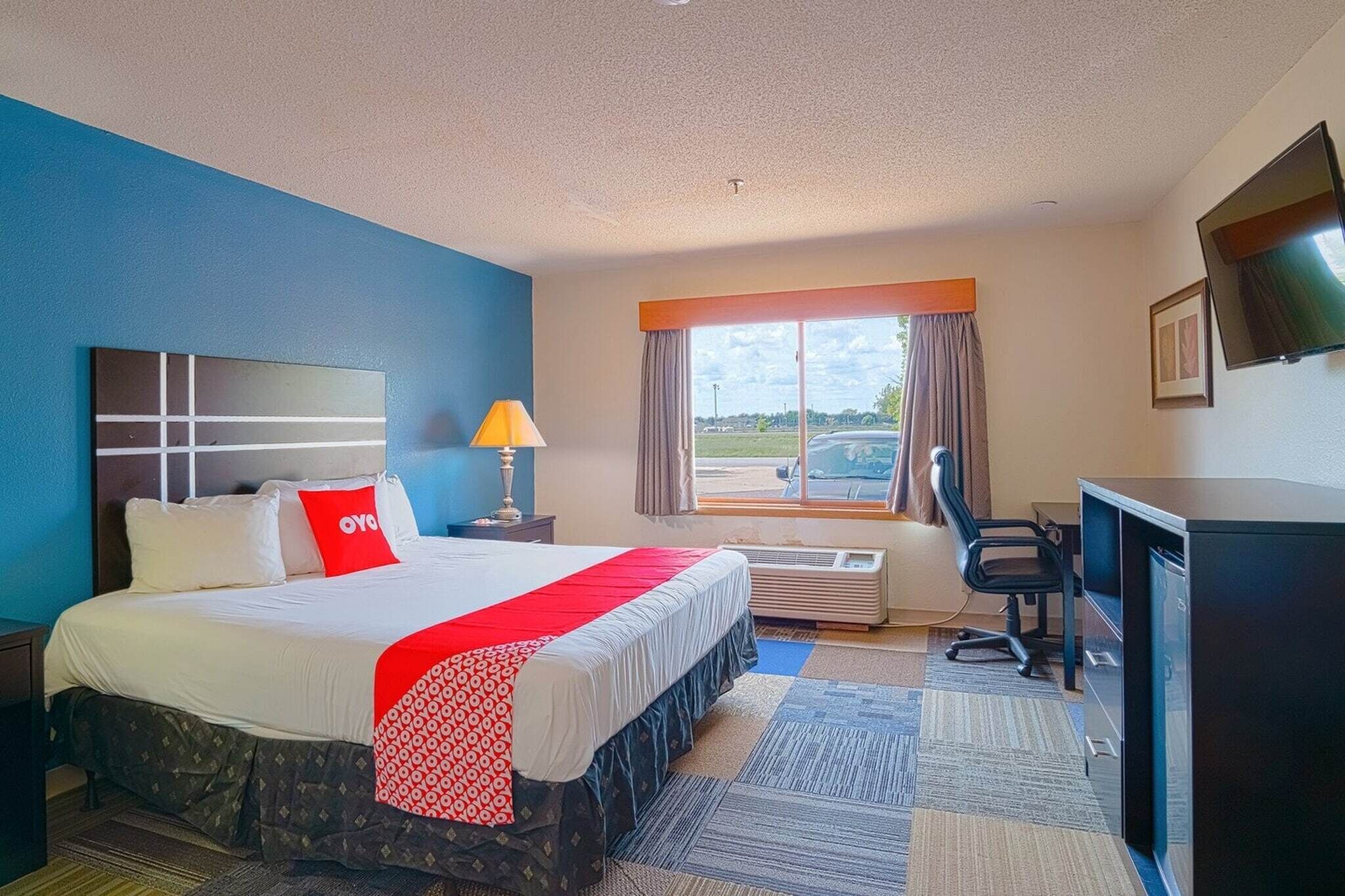 Een hotelkamer met een bed, bureau, stoel, televisie en raam met uitzicht.