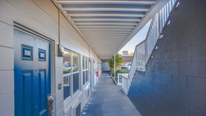 A corridor with a blue door, windows, and a covered walkway.