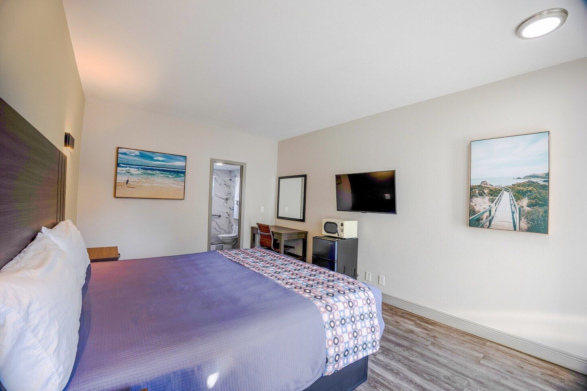Ein Hotelzimmer mit Bett, Fernseher, Schreibtisch und Stuhl.