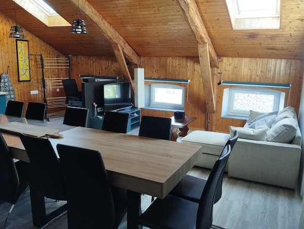 Un intérieur en bois comprenant une table à manger, des chaises, un canapé, un téléviseur et une fenêtre.