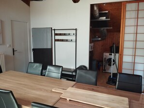 Une pièce comprenant une table à manger en bois, des chaises noires, un tableau blanc, un étendoir à linge et un lave-linge.