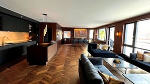 A modern interior with a kitchen, dining area, and seating space with large windows.
