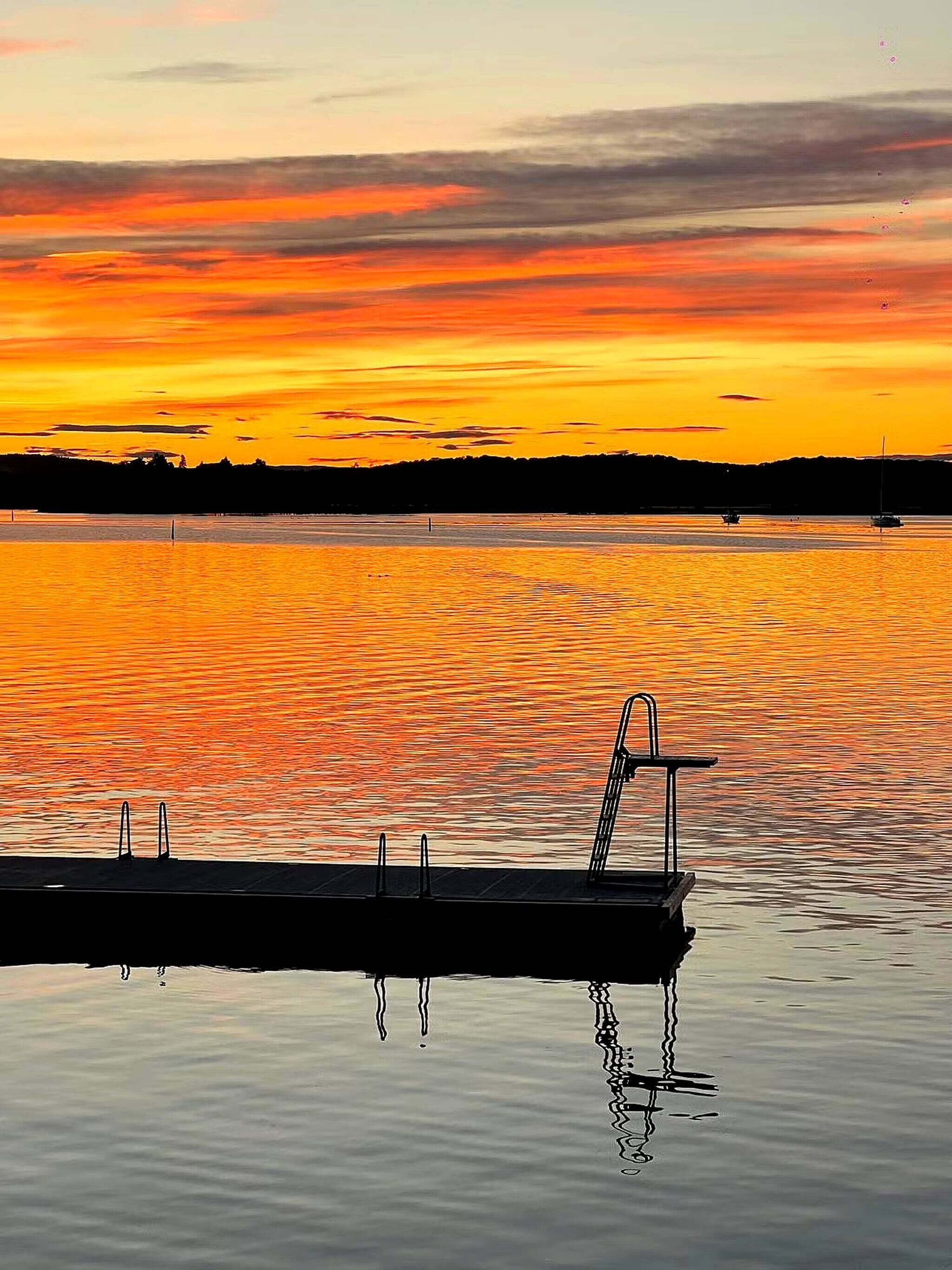 A calm body of water with a dock extending into it.