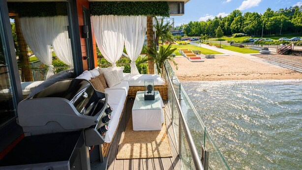 A balcony with a grill, white sofa, and a glass table.