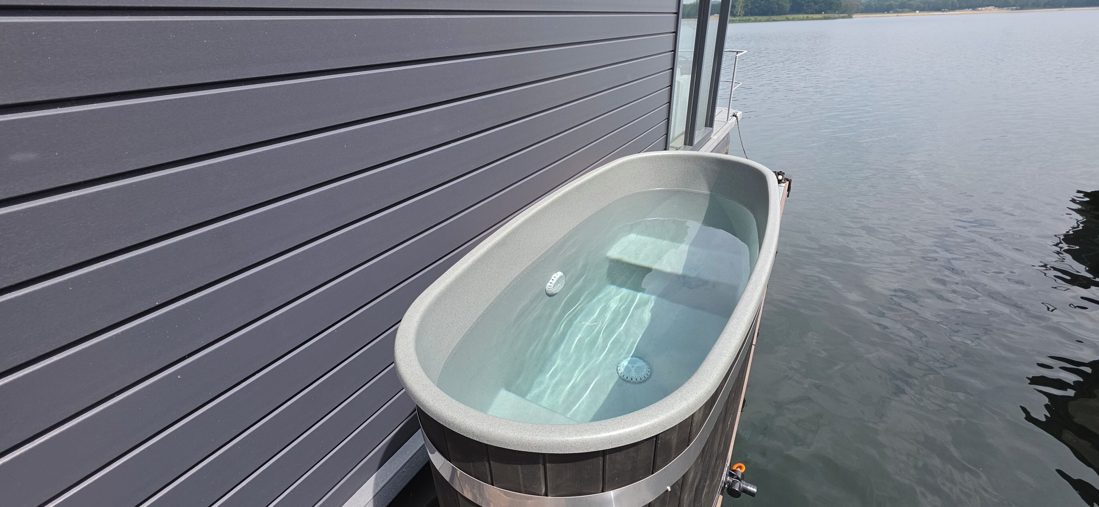 Una vasca idromassaggio adiacente a un edificio, con vista su acqua calma.