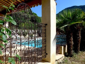 Une entrée sécurisée, avec une piscine, des palmiers et une chaîne de montagnes en arrière-plan.