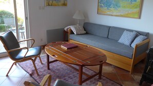 Una sala de estar con un sofá, dos sillas, una mesa de centro de madera y un tapete estampado.