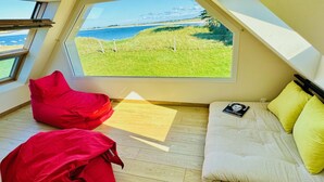 Ein Zimmer mit einem großen Fenster, einem Bett, einem roten Sitzsack und einem Holzboden.