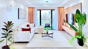 Een moderne woonkamer met een bank, salontafel en grote ramen.