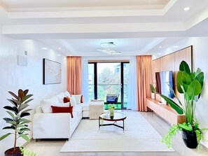 A modern living room with a sofa, coffee table, and large windows. - Shamm dream riverside (Nairobi)