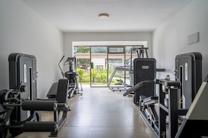 A gym with cardio machines, weight stations, and a view of greenery outside. - Shamm dream riverside (Nairobi)
