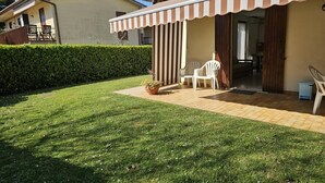 Uma casa com alpendre coberto, gramado e sebes.