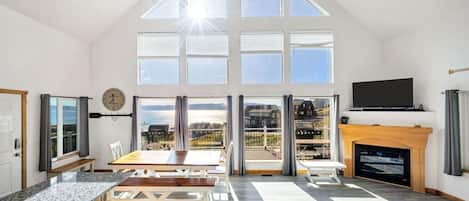 Un loft espacioso con techo alto, ventanas grandes, zona de comedor, sala de estar con sofá y chimenea.