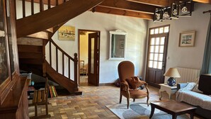 Un salon spacieux avec un parquet en point de Hongrie, un escalier en bois, un grand fauteuil, un canapé et une table basse.