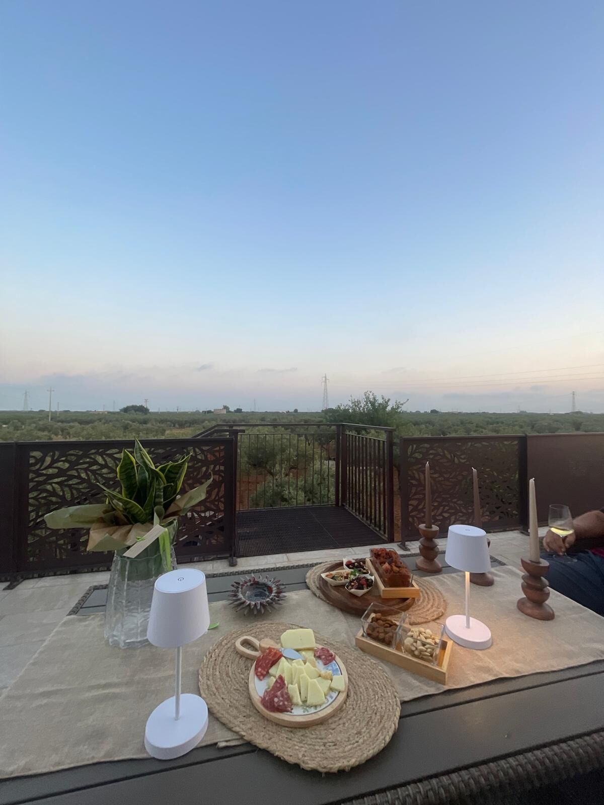 Un tavolo apparecchiato con cibo e bevande su un balcone con vista sul paesaggio.