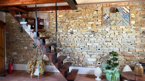 A rustic interior with a stone wall, wooden staircase, and a decorative wheel. - The tranquility of the countryside, just a stone's throw from the sea and the Selinunte Archaeological Park (Sicilia)