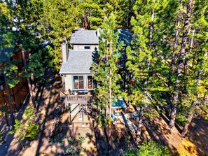 Una casa a due piani circondata da alberi rigogliosi, con una terrazza e una zona relax all'aperto.