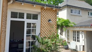 A residential building with a garage door, a wooden lattice wall, and a garden area with potted plants.