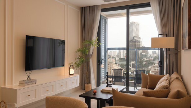 Een moderne woonkamer met een flatscreen televisie, een bank, een eettafel en een groot raam met uitzicht op de stad.