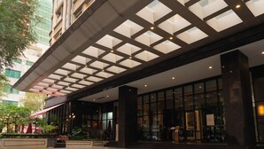 Een hotelentree met een overdekt terras, grote ramen en een modern architectonisch ontwerp.