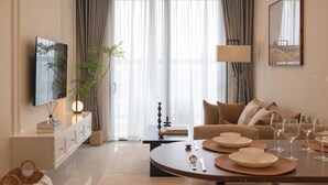 Een moderne woonkamer met een eethoek, een flatscreen-televisie, een bank, een salontafel en een kroonluchter.
