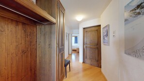 Ein Flur mit Holztüren, einer Bank und einem Bett im Hintergrund.
