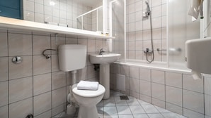 Een moderne badkamer met toilet, wastafel en douche.