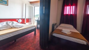Een hotelkamer met twee bedden, een rood tapijt, een schilderij aan de muur en uitzicht door het raam.