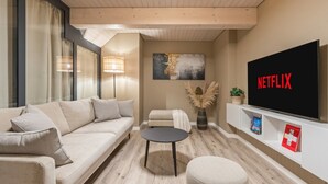Un salon moderne avec un canapé, une table basse, un téléviseur et une bibliothèque.