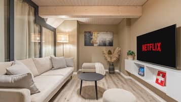 Una sala de estar moderna con un sofá, una mesa de centro, un televisor y una estantería.