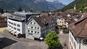 Une ville où se côtoient des bâtiments modernes et traditionnels, une église et, en arrière-plan, des montagnes.
